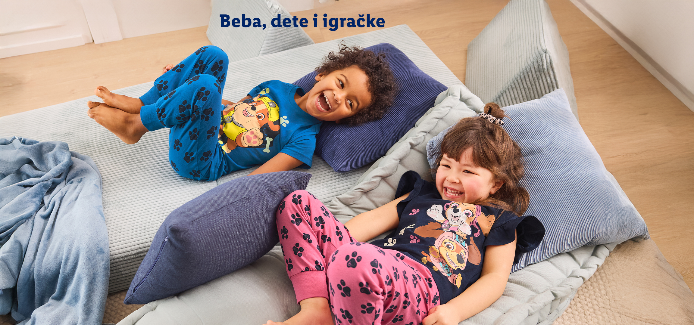 Dvoje dece u pidžamama sa šapama, jedno crta na svetlećoj tabli. Tekst: Beba, dete i igračke.