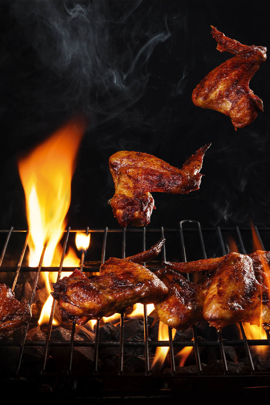 Pileća krilca na roštilju sa plamenom i dimom.