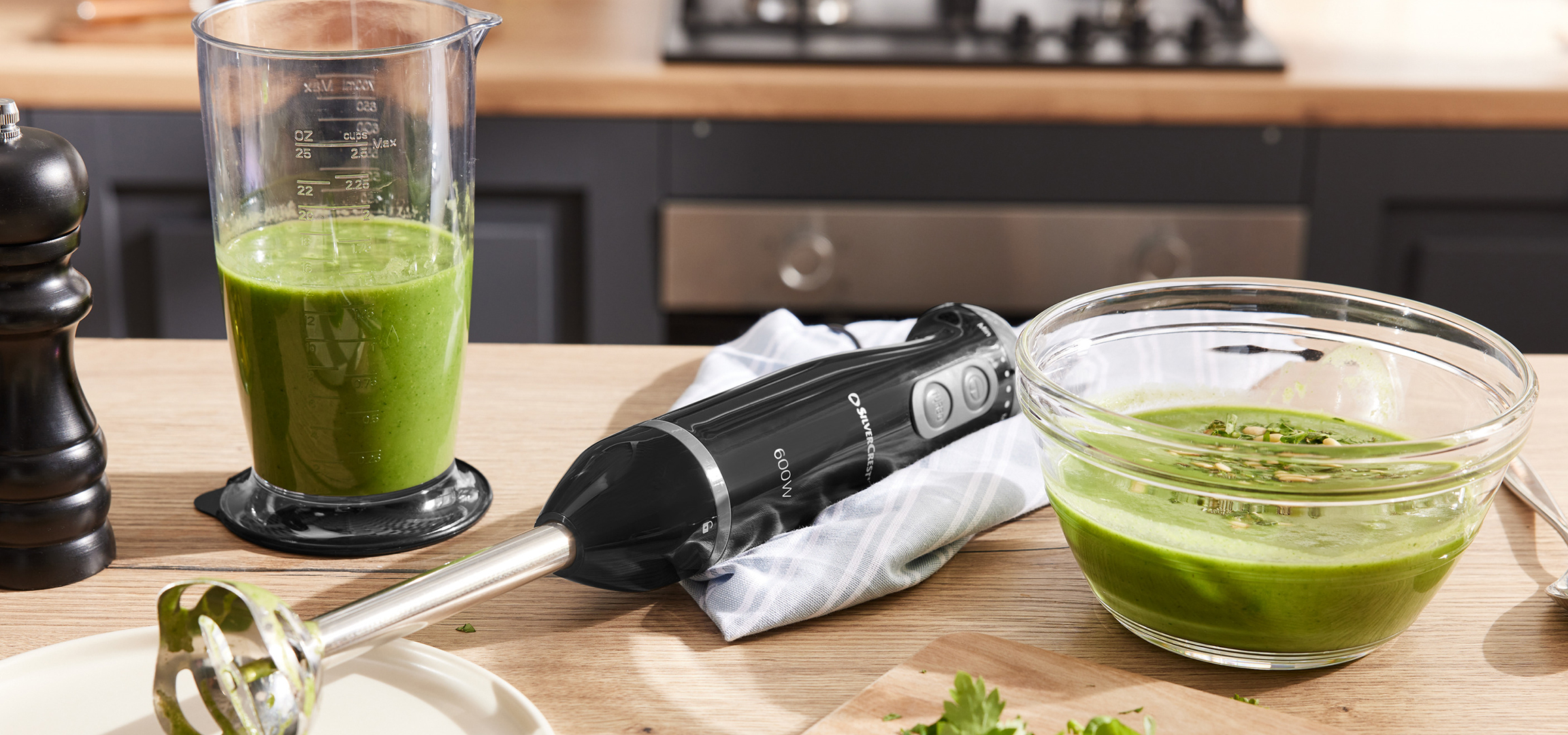 Štapni mikser Silvercrest, posuda sa zelenim smutijem, grejna ploča sa posudama za hranu i tiganj za palačinke.