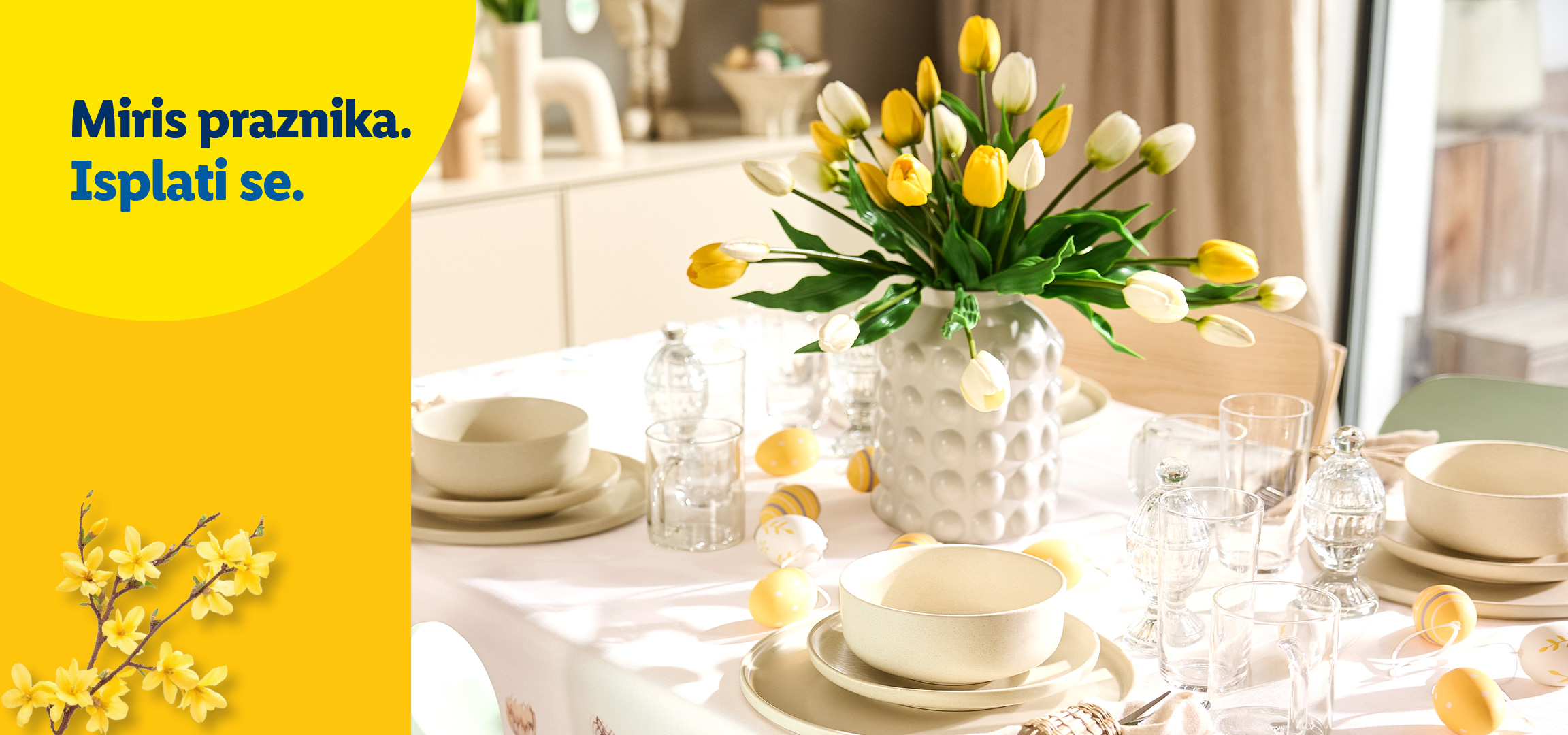 Žuti i beli tulipani u vazi na stolu sa posuđem i tekstom: „Miris praznika. Isplati se.“