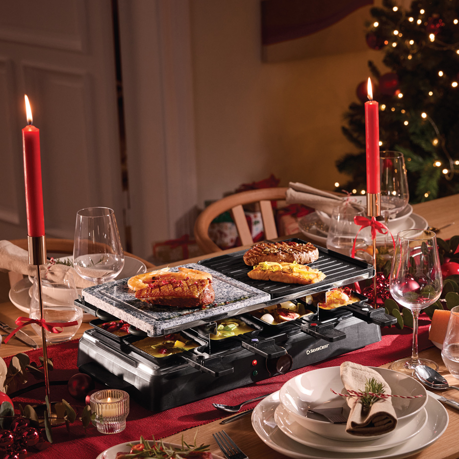 SilverCrest raclette roštilj sa mesom i sirom na prazničnom stolu sa svećama i jelkom.