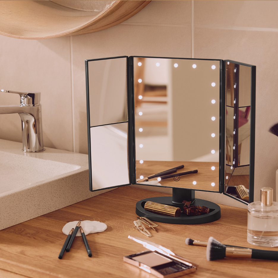 Ogledalo sa LED osvetljenjem na drvenoj radnoj površini sa šminkom i četkicama.