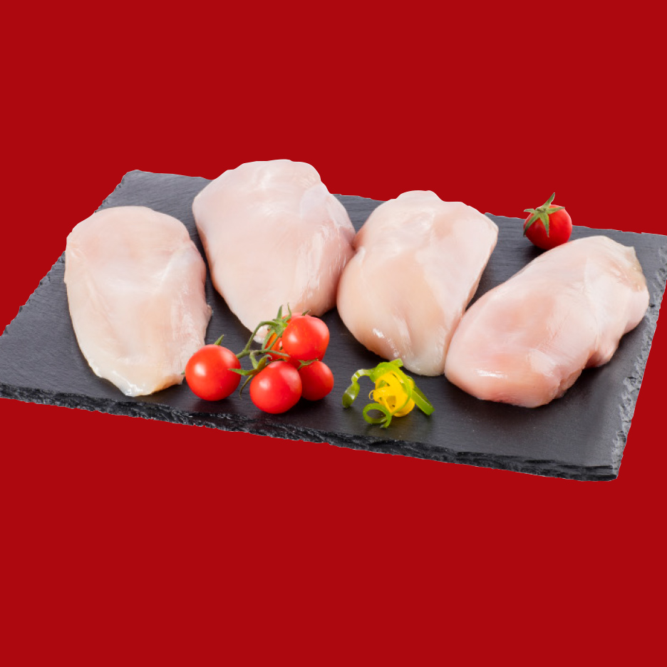 Sveža pileća prsa na crnoj ploči sa paradajzom i ukrasima.