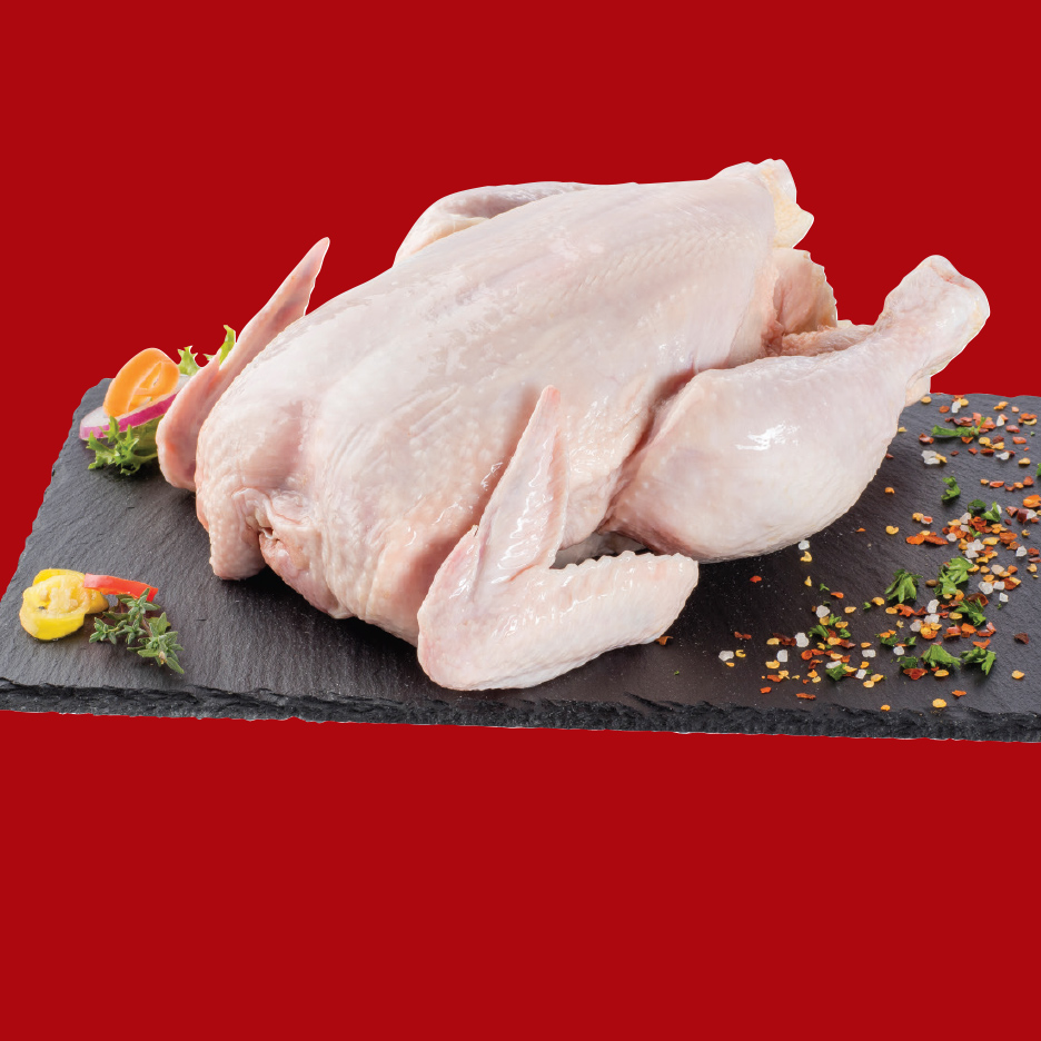 Sveže celo pile na crnoj ploči sa začinima i povrćem.