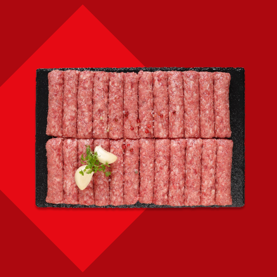 Sveži ćevapi na crnoj ploči, ukrašeni belim lukom i peršunom.