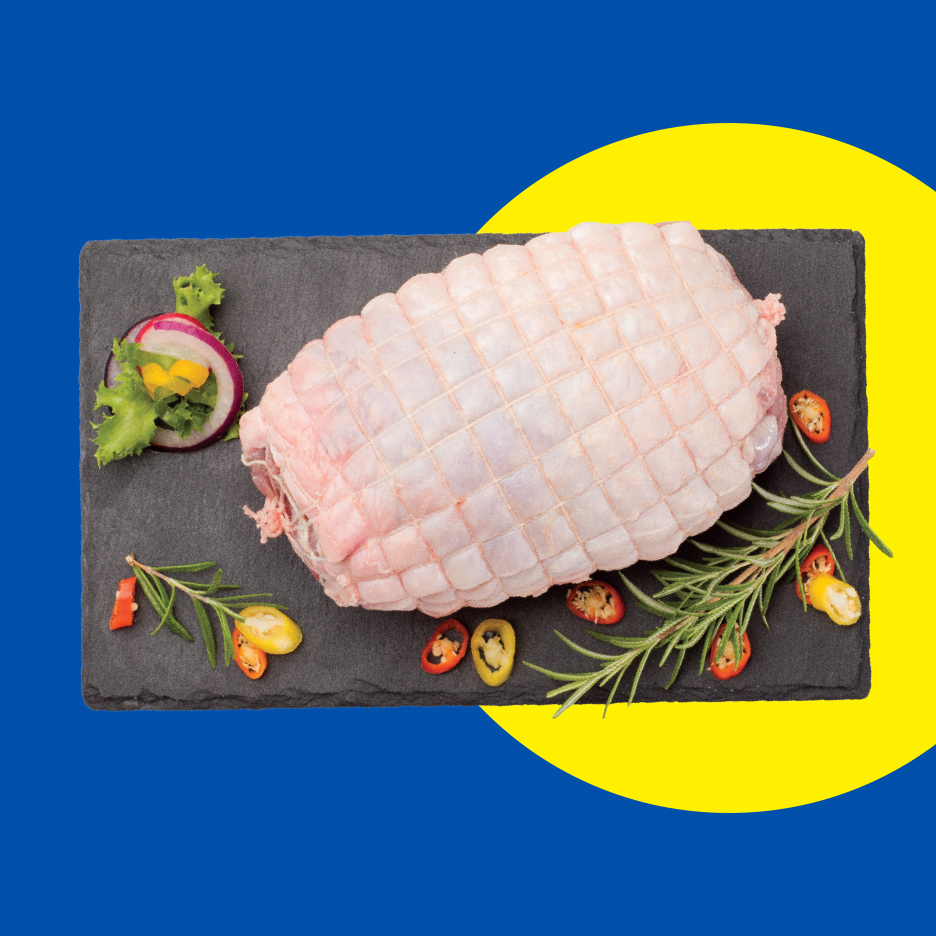 Sveže rolovano meso sa začinima na crnoj ploči, na plavo-žutoj pozadini.