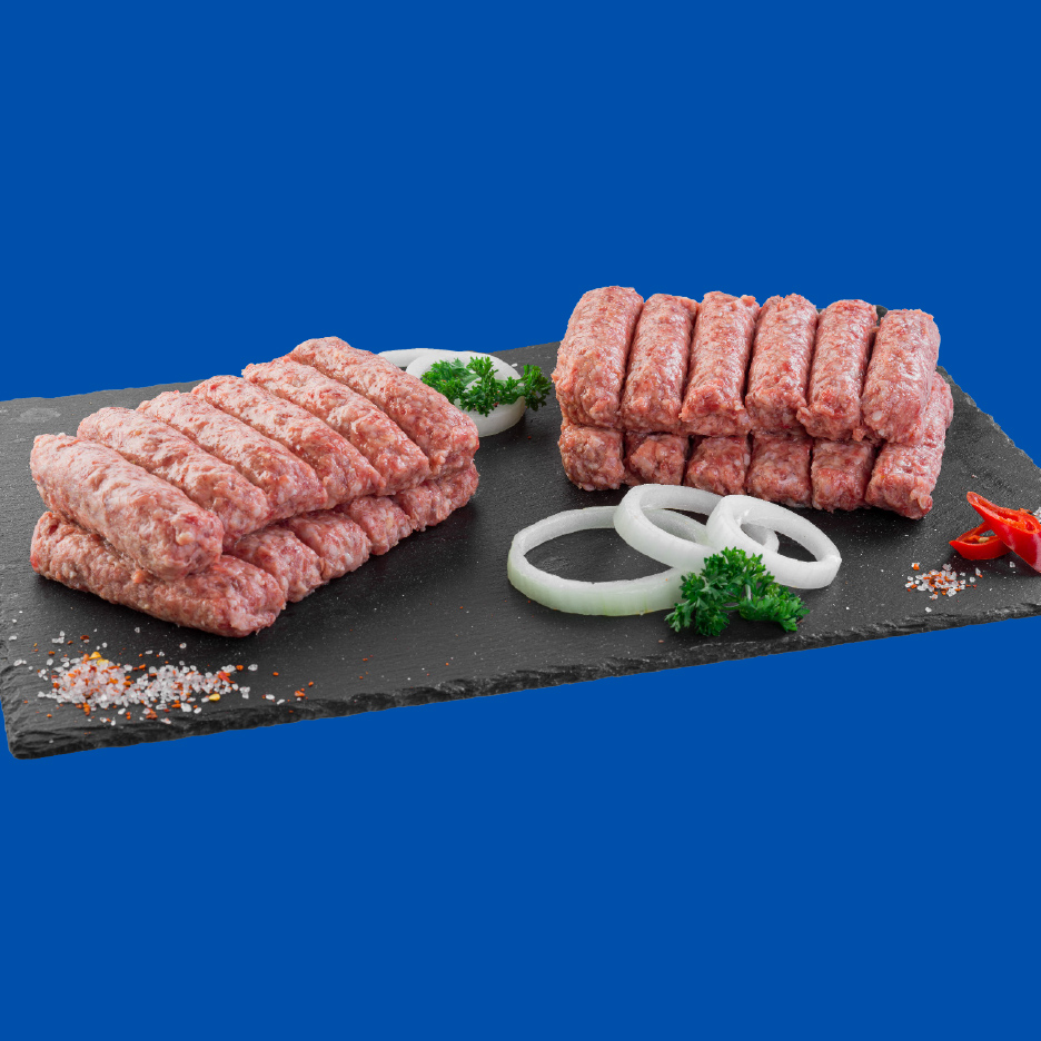 Sveži ćevapi na crnoj ploči sa lukom, peršunom i začinima.