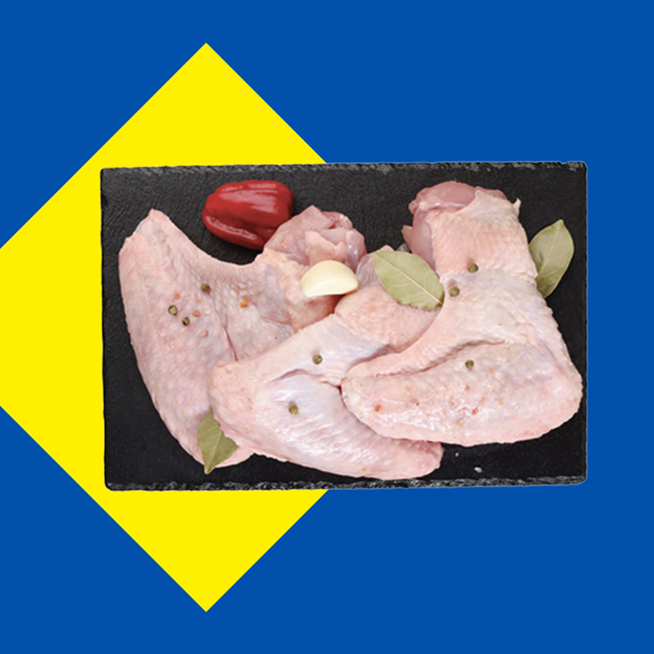 Sveža pileća krilca sa začinima na crnoj ploči, na plavo-žutoj pozadini.