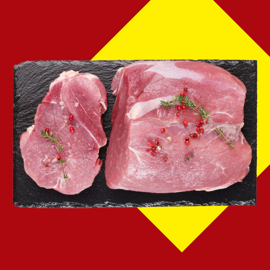Sveže svinjsko meso na crnoj ploči, ukrašeno začinima, na crveno-žutoj pozadini.