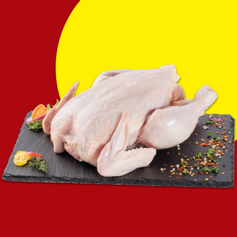 Sveže celo pile na crnoj ploči sa začinima i povrćem.