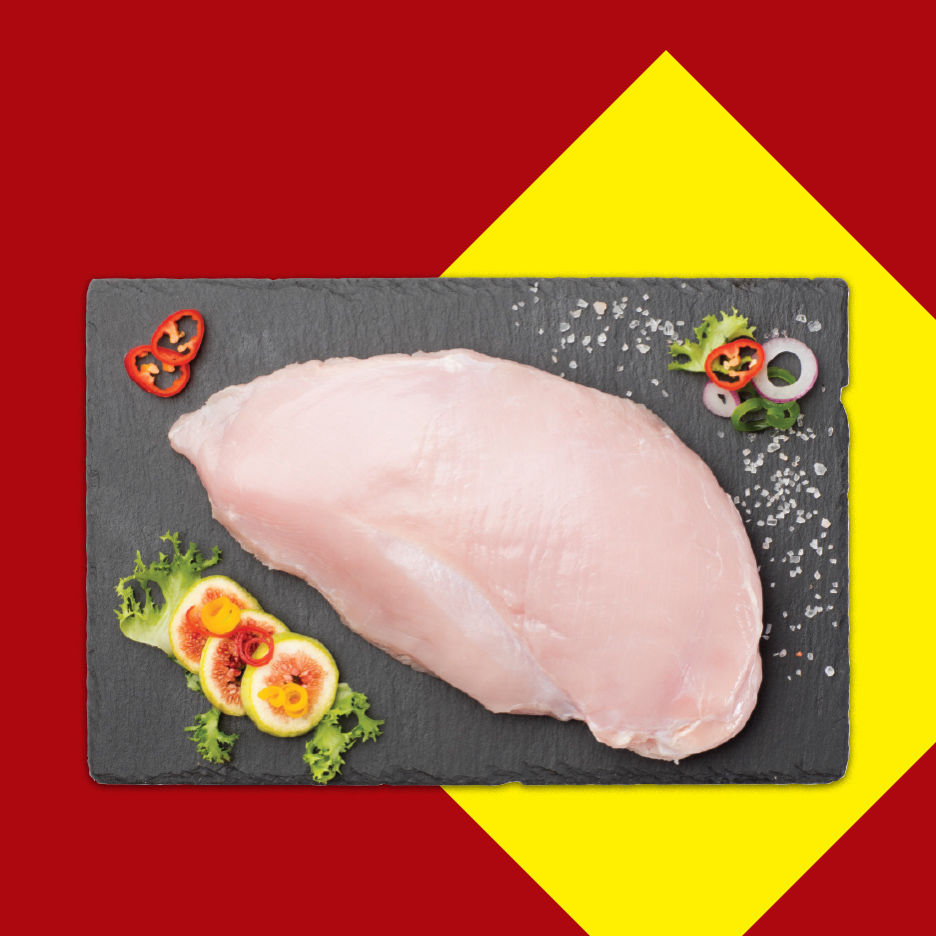 Sveža pileća prsa na crnoj ploči sa začinima i ukrasima.