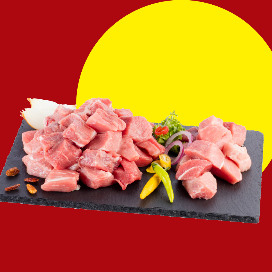 Sveže isečeno svinjsko meso na kockice sa začinima na crnoj ploči.