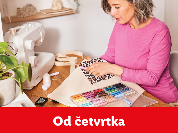 Žena šije torbu sa leopard printom, pored mašine za šivenje i kutije konca.