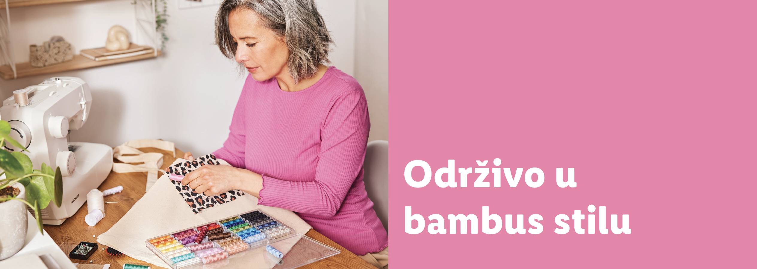 Žena šije, sa mašinom za šivenje i koncem na stolu.