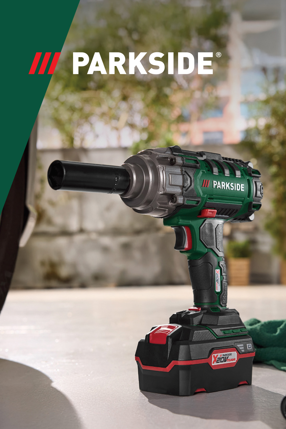 Akumulatorski udarni odvijač sa baterijom i nasadnim ključem na betonskoj površini.