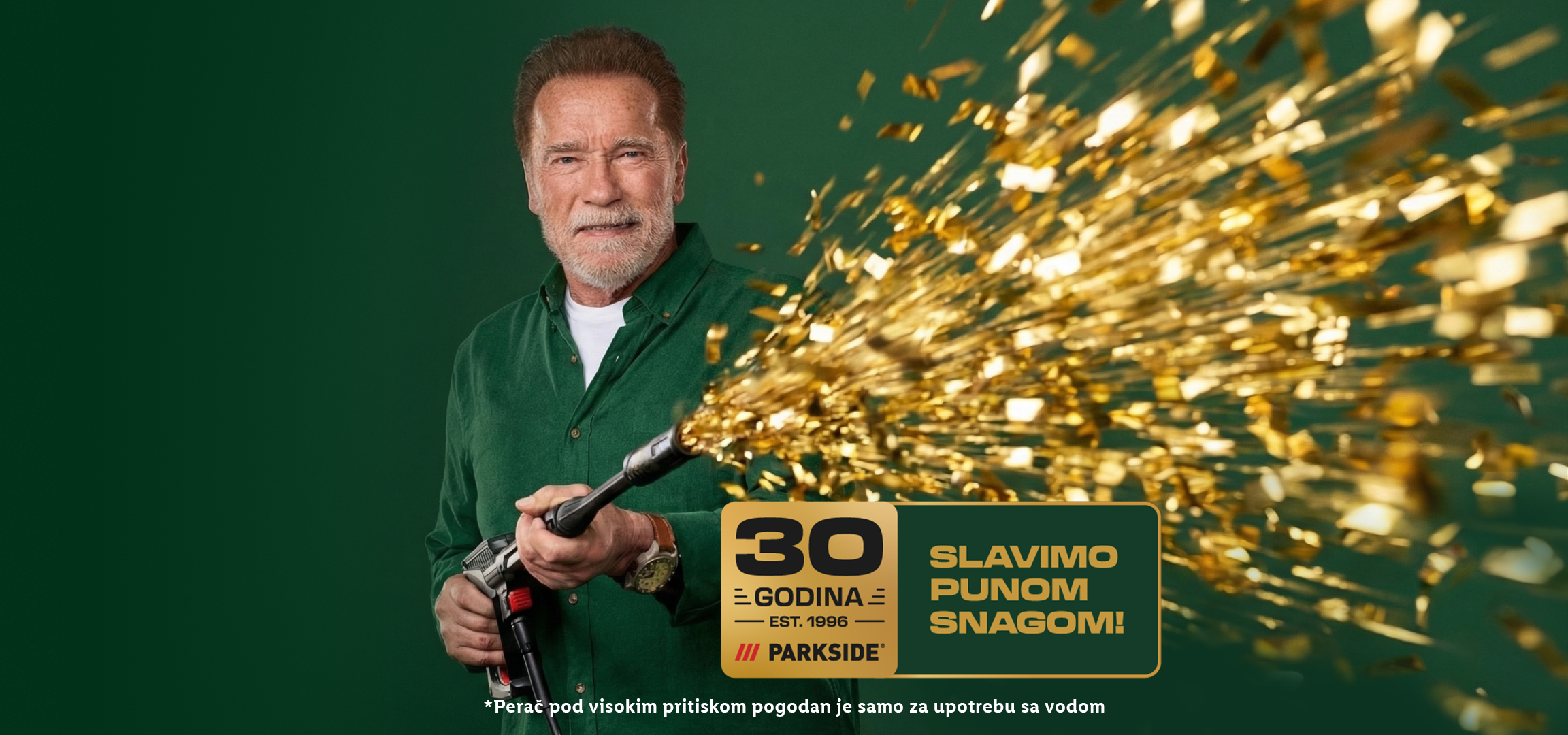 Muškarac sa bradom drži alat koji ispaljuje zlatne konfete, sa natpisom 'Slavimo punom snagom!' i '30 godina'.