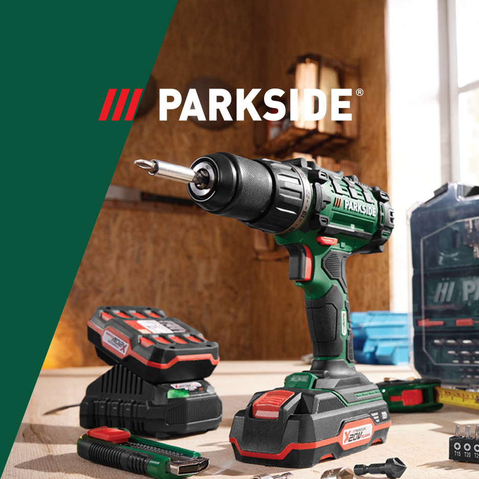 Parkside akumulatorska bušilica, baterija i punjač na drvenom stolu u radionici.