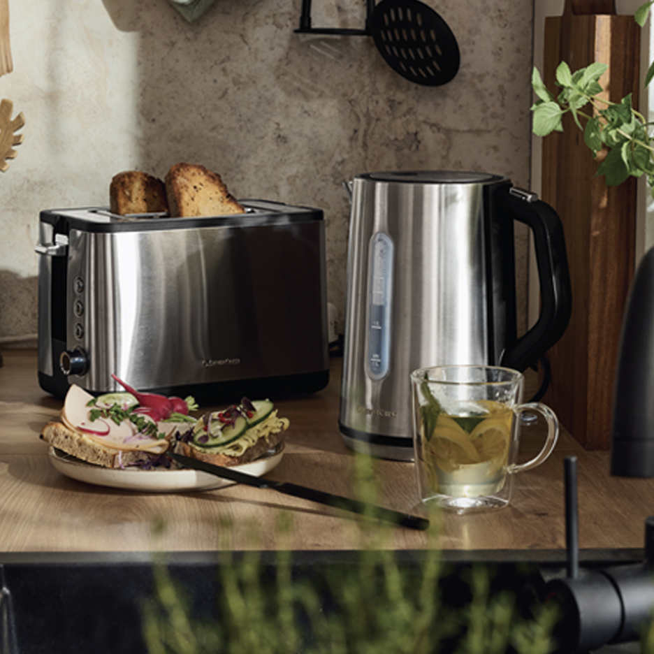 Toster i kuvalo za vodu od nerđajućeg čelika na kuhinjskom pultu sa tostom i sendvičima.