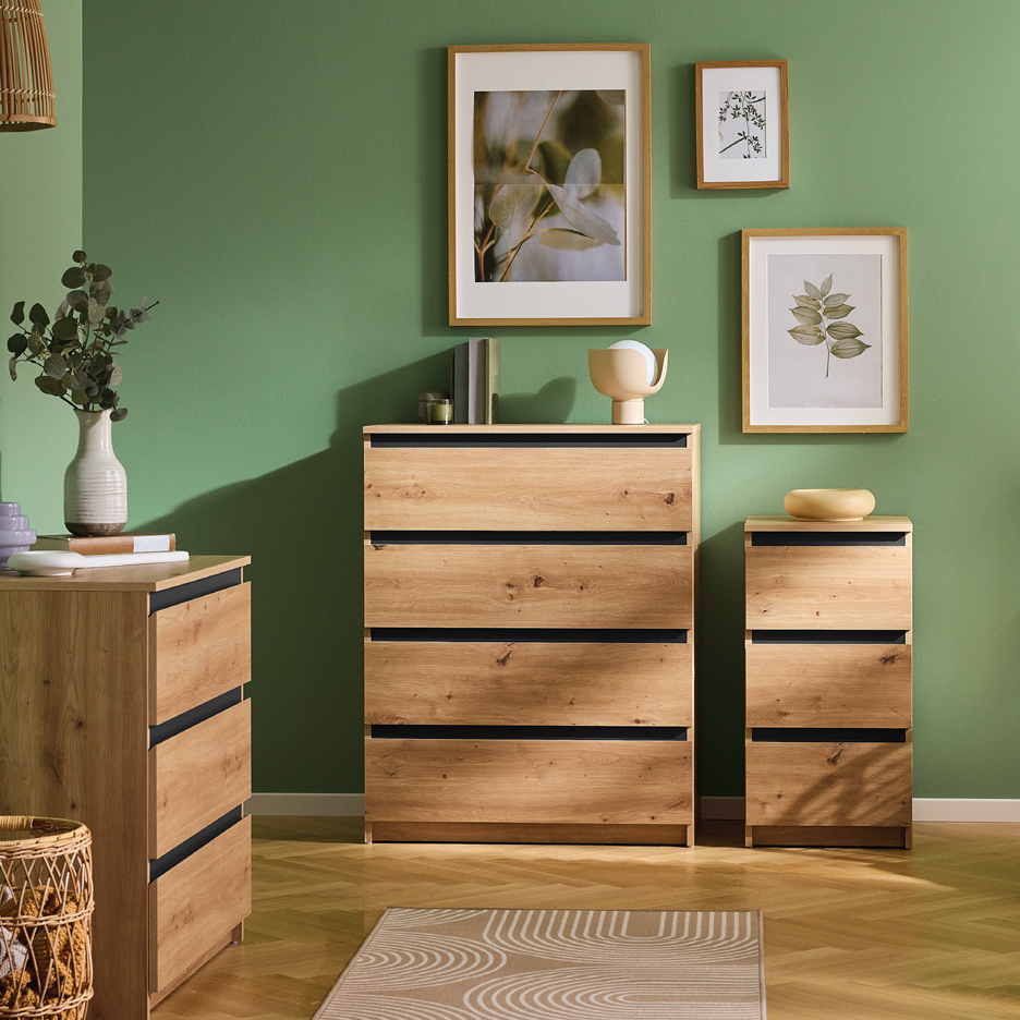 Drvene komode sa fiokama u sobi sa zelenim zidovima i slikama.