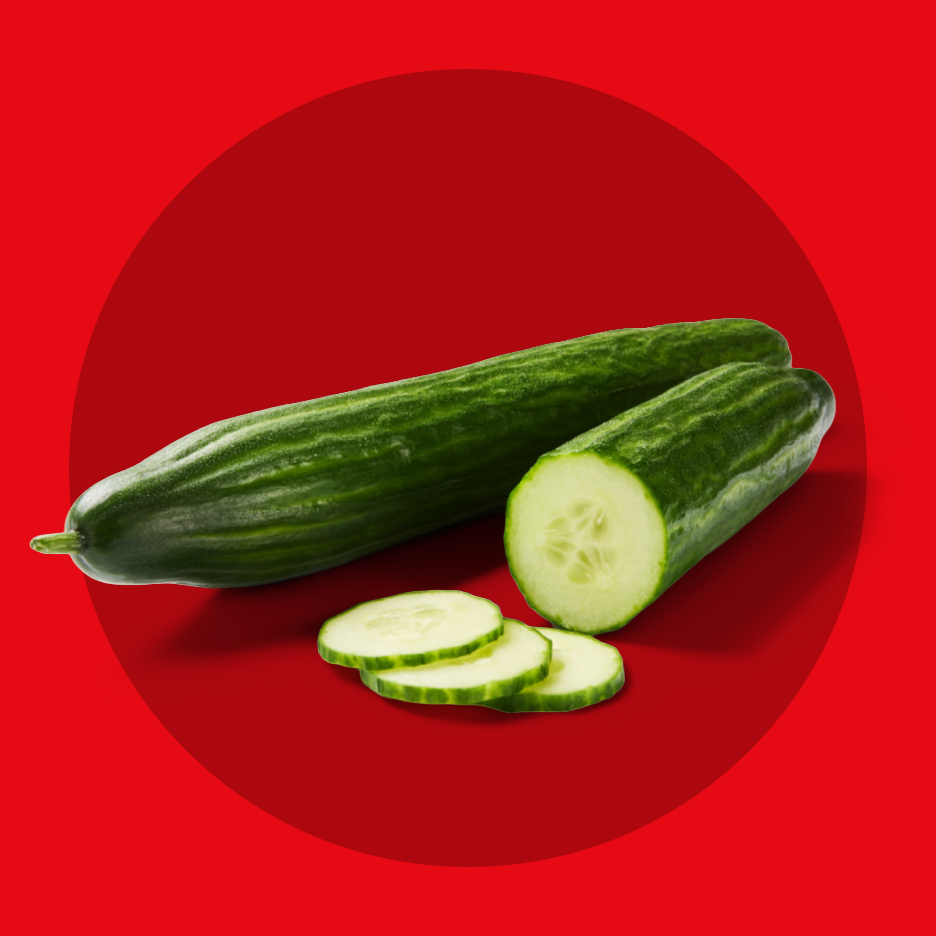 Dva krastavca, jedan ceo i jedan isečen na kolutove, na crvenoj pozadini.