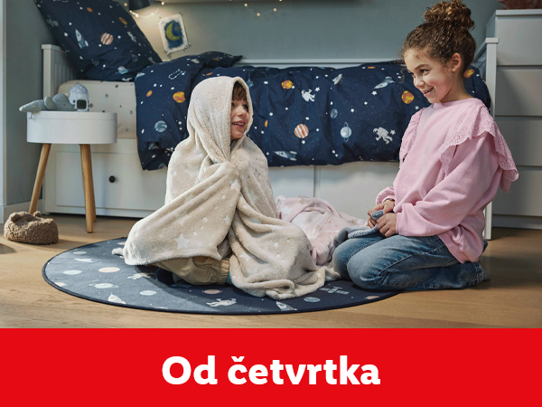 Dvoje dece se igra na podu sa ćebetom i okruglim tepihom sa svemirskom temom.