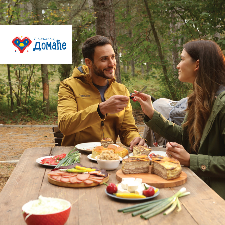 Par uživa u pikniku sa tradicionalnom hranom, uključujući pitu, suhomesnate proizvode i sir.